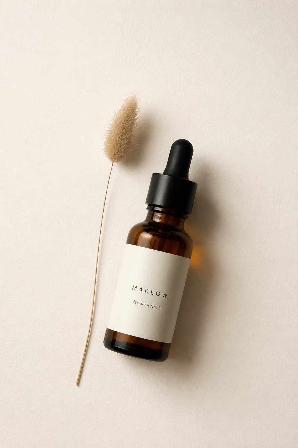 Generated still: the bottle lying on textured paper beside a dried grass stem, shot top-down